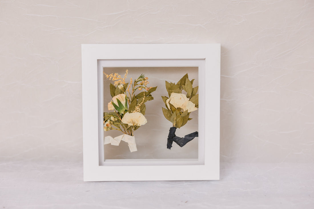 Two boutonnieres pressed into a small white 6x6 wedding frame design
