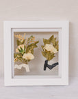 Two boutonnieres pressed into a small white 6x6 wedding frame design