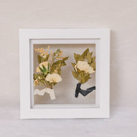 Two boutonnieres pressed into a small white 6x6 wedding frame design