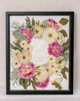 Black wood 16x20 frame with a pressed flower design with wedding invite on white background