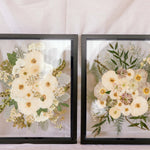 Two black wood frames with pressed wedding bouquets inside