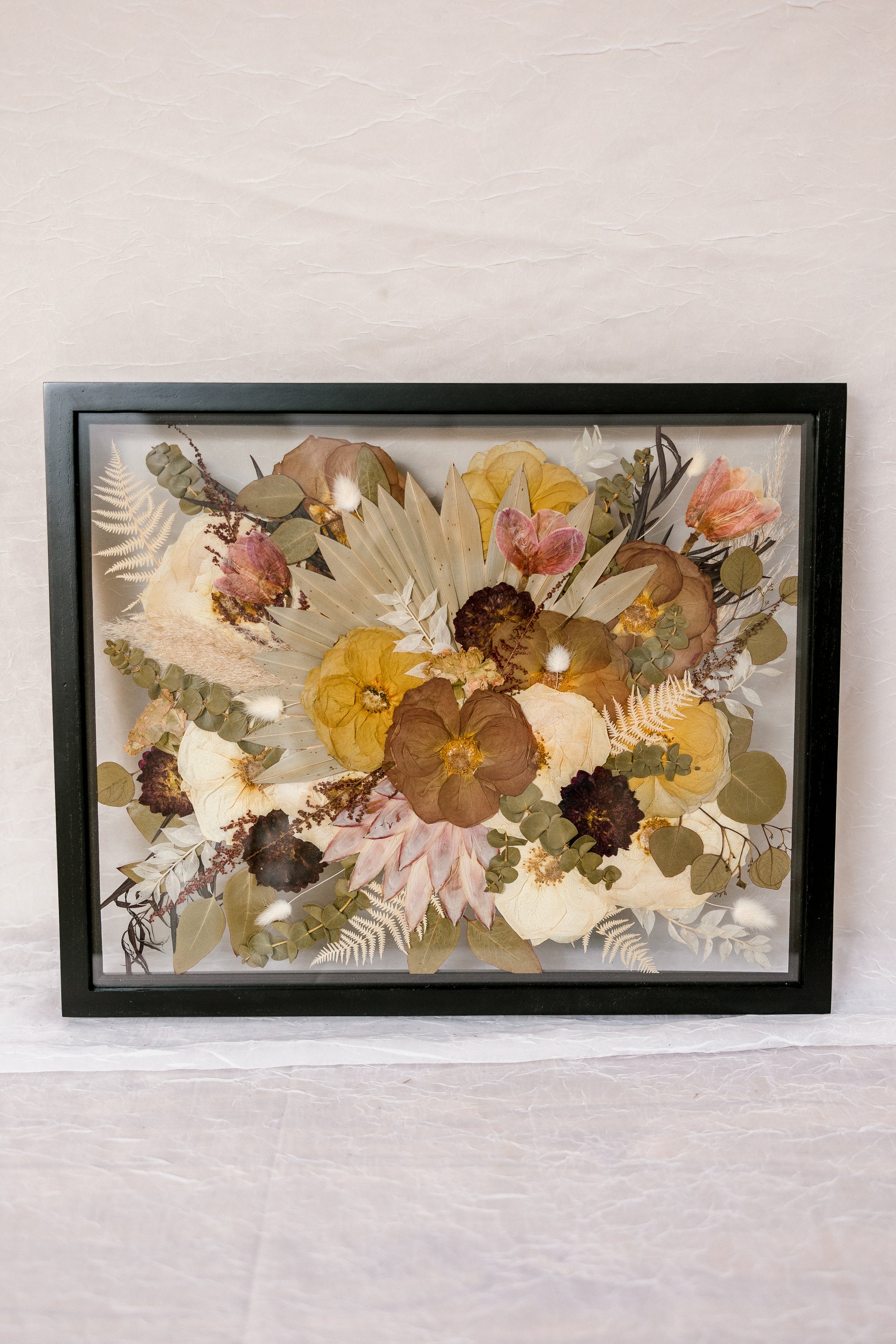 Pressed flower wedding bouquet design in a 16x20 black wood frame standing horizontally