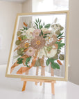 A gold wood frame with pressed flowers from a bridal bouquet, detailed by the ribbon that surrounded the wedding flower stems. 