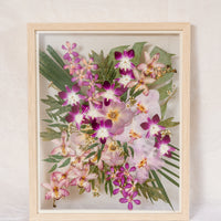 A bright and vibrant pink and green bouquet made up of orchids and roses has been pressed and framed in a natural wood bouquet preservation frame.