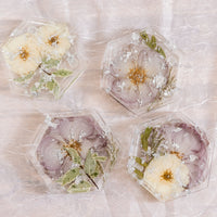 Pressed flower resin coasters in a hexagon shape with silver metallic flakes